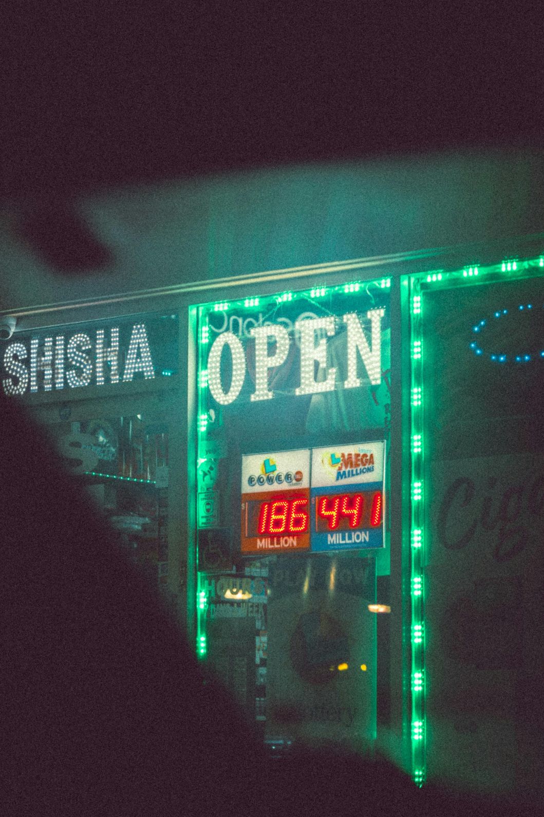 Storefront of a smoke shop in Houston with a glowing “Shisha” and “Open” sign.