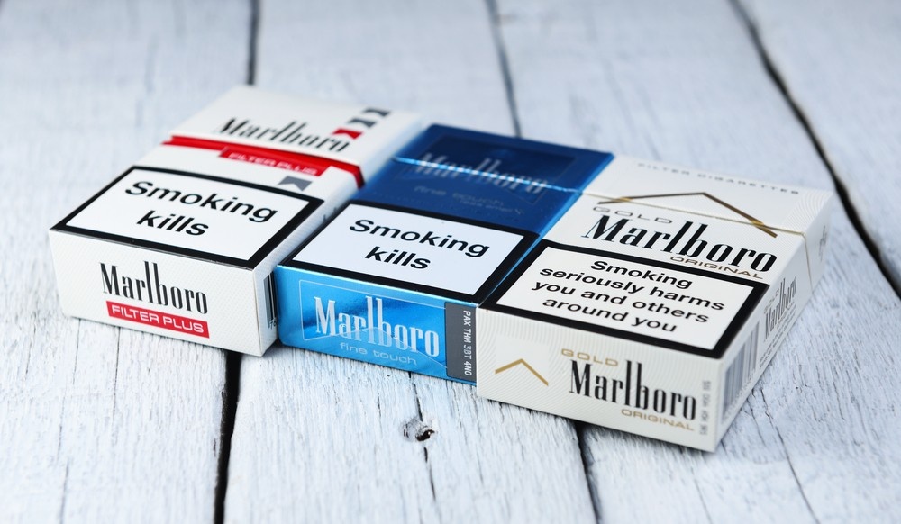 Assorted Marlboro cigarette packs including Filter Plus, Fine Touch, and Gold Original on light wood surface, ideal for tobacco shop product display.