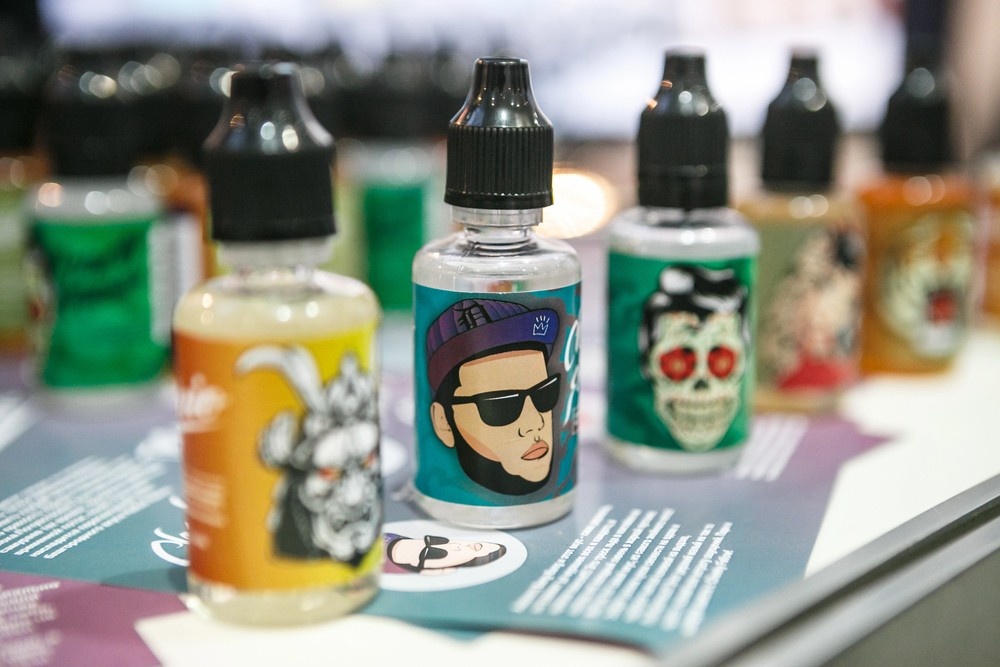 Colorful array of e-liquid bottles with fun cartoon labels like skulls and characters on display, perfect for vapers visiting smoke shop Houston for unique flavors.
