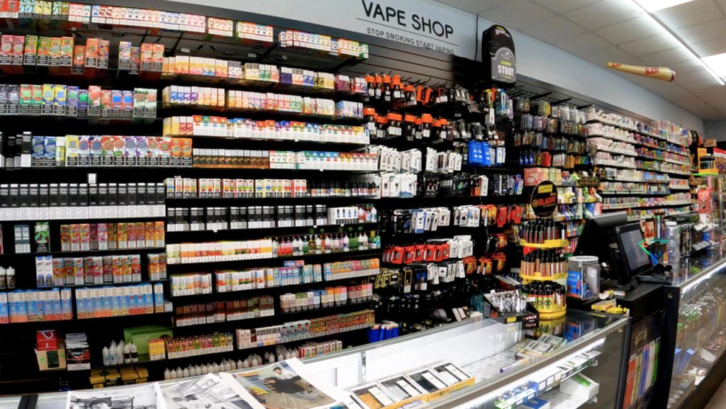 Extensive wall shelving and glass counters stocked with vape juice in a premier smoke shop Houston store.