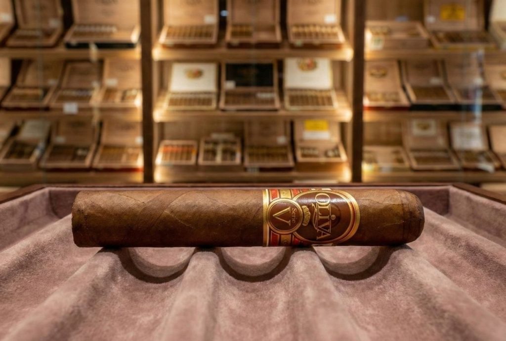 A premium Oliva Serie V cigar rests on a velvet tray inside a well-stocked walk-in humidor at a leading cigar shop Houston.