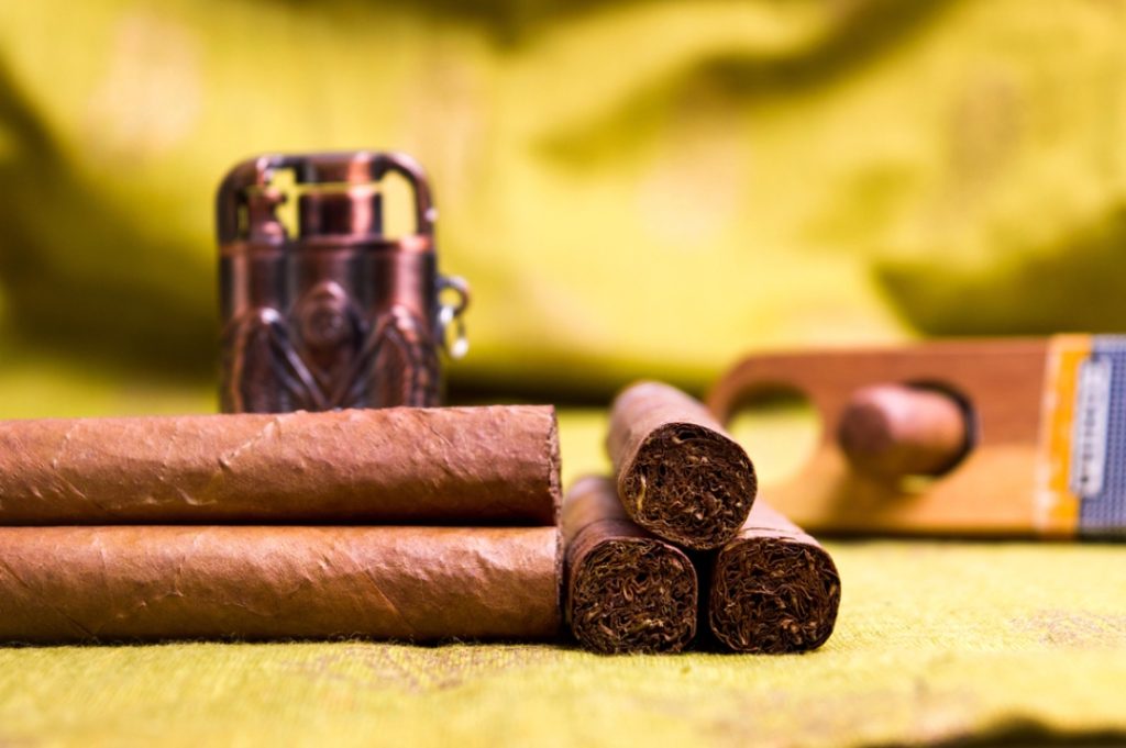 Close-up of premium, hand-rolled cigars, an elegant lighter, and a cutter, all available at a tobacco shop Houston.