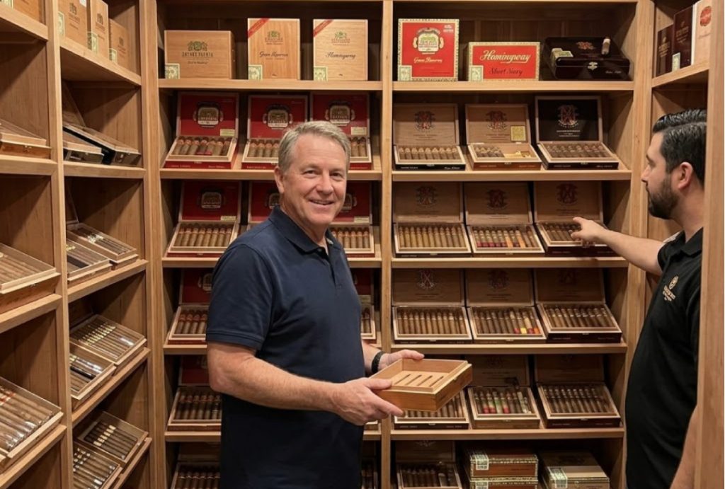 A customer holds a custom humidor while browsing a wide collection of rare cigars in a large cigar shop houston.
