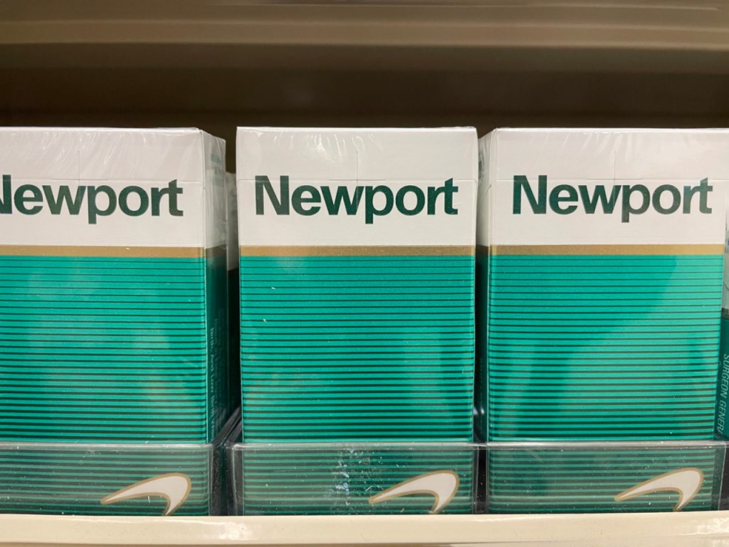 A row of three classic Newport white and green cigarette packs in a retail shelf display at a cigarette shop Houston.