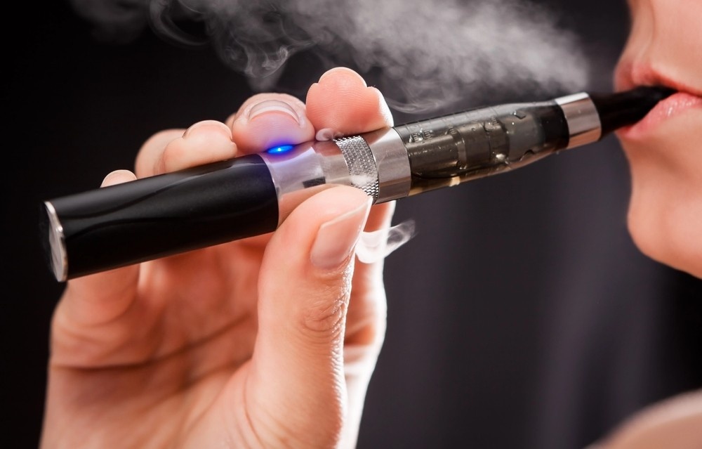A close-up view of a person using a refillable black vape pen, a popular choice among premium e-cigarettes houston.