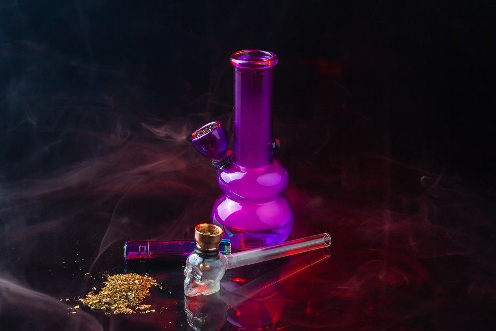 A purple water pipe and skull pipe display with dry herb, showcasing diverse products at our smoke accessories Houston.