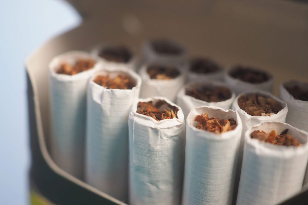 Detailed close-up of fresh tobacco-filled cigarette ends inside an open pack. Inventory from a cigarette shop Houston.