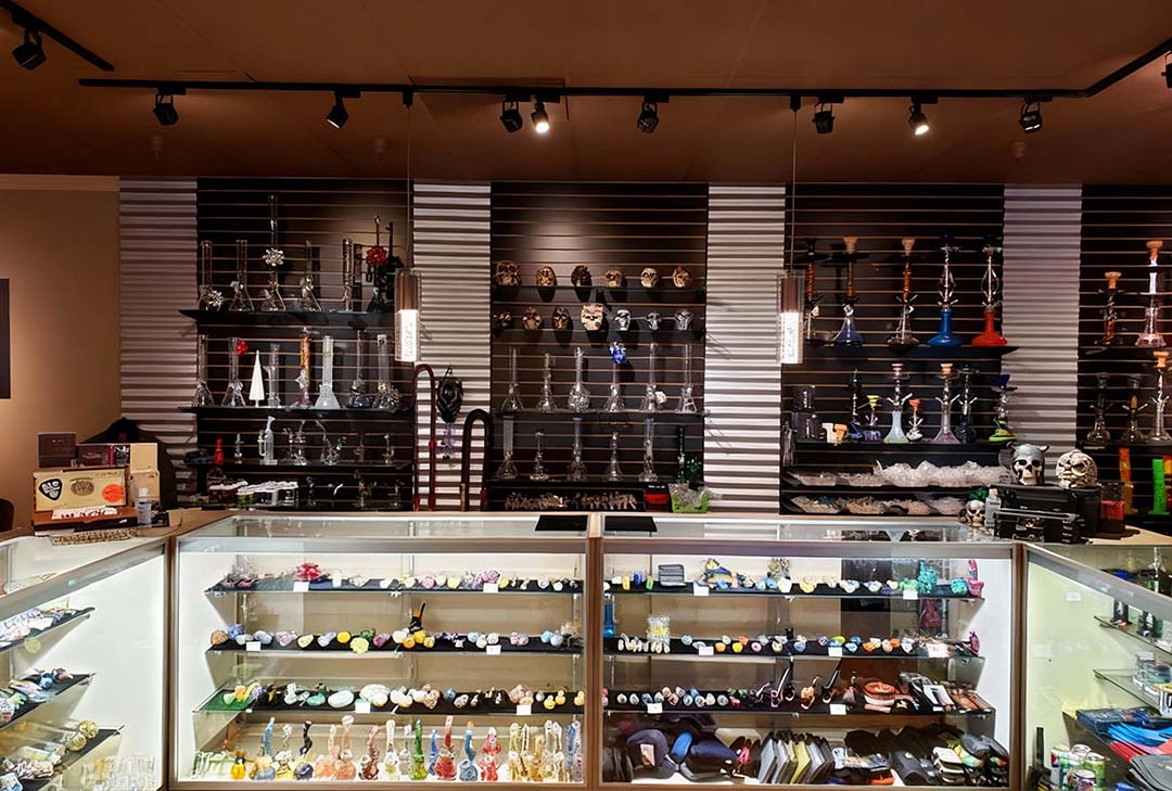 Fully stocked Head Shop Houston with colorful bongs, vapes & smoking gear under spotlights.