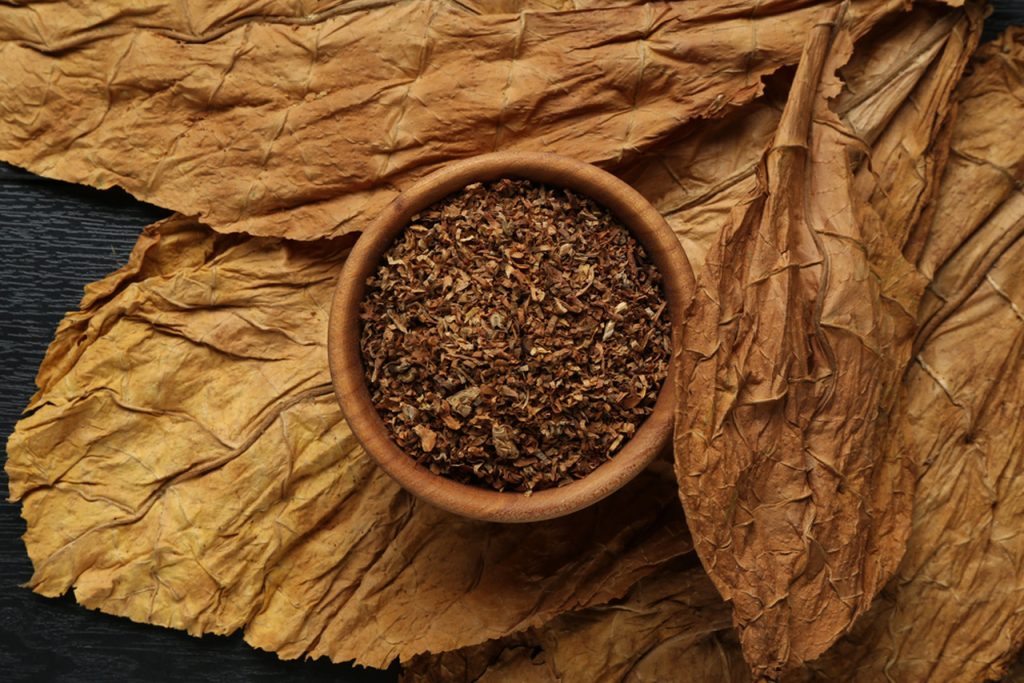Finely cut premium tobacco in wooden bowl with cured leaves, sourced from leading tobacco shop Houston