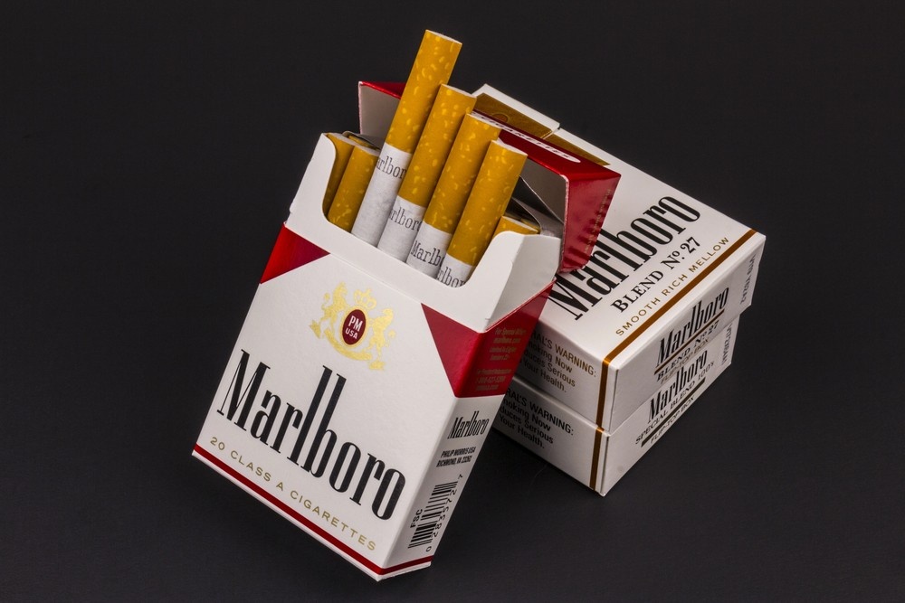 Open pack of Marlboro Blend No. 27 cigarettes spilling out onto black background, classic red and white design, perfect view for tobacco shop inventory.