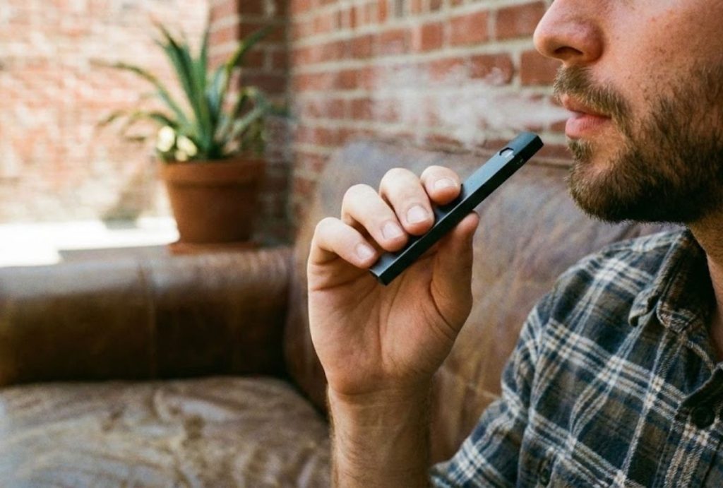 E-cigarettes Houston blend comfort and style—vaper relaxes indoors with visible vapor and casual vibe.