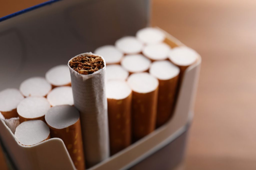 Single reversed cigarette with visible tobacco stands out among white filters in an open pack. Sold at cigarette shop Houston.